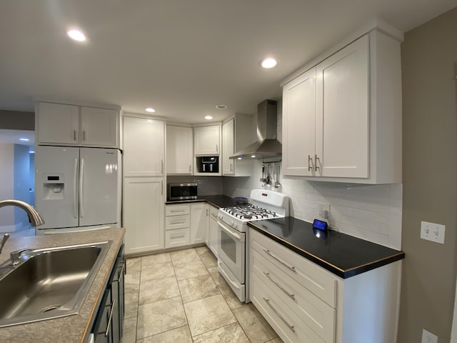 kitchen with sink, white cabinetry, white appliances, wall chimney range hood, and backsplash