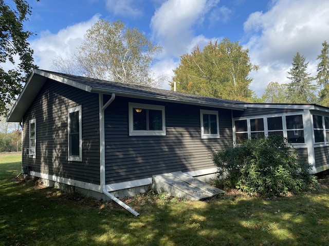 view of home's exterior featuring a sunroom and a lawn