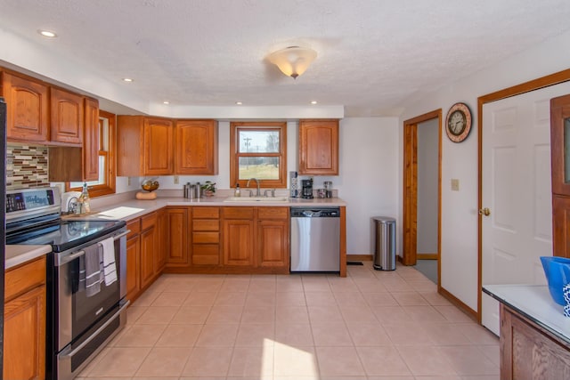 kitchen with light tile patterned flooring, appliances with stainless steel finishes, sink, and backsplash