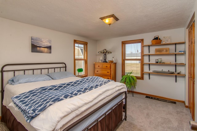 bedroom featuring light colored carpet and a textured ceiling