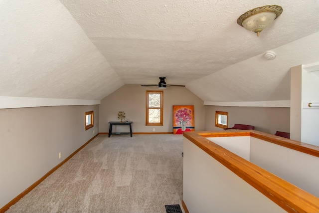 bonus room featuring vaulted ceiling, light carpet, and a textured ceiling