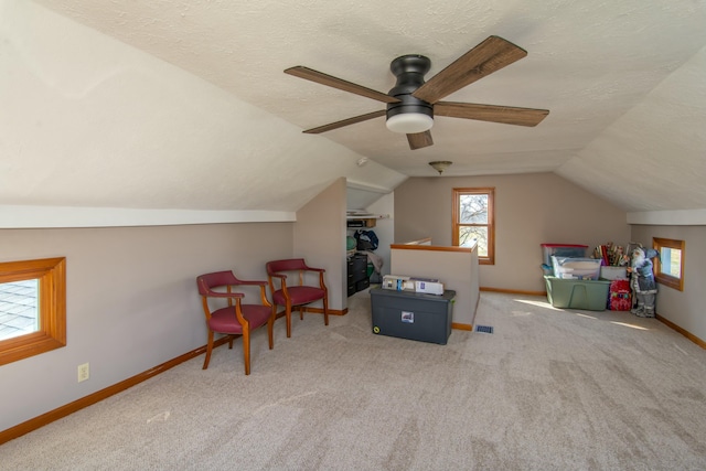 interior space featuring ceiling fan, lofted ceiling, carpet flooring, and a textured ceiling