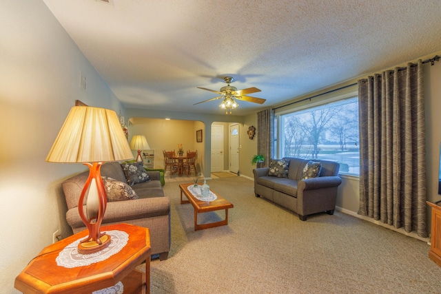 living room with ceiling fan, light colored carpet, and a textured ceiling