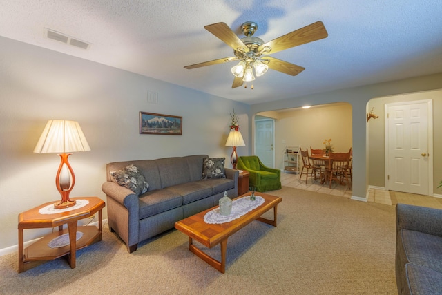 carpeted living room featuring ceiling fan and a textured ceiling