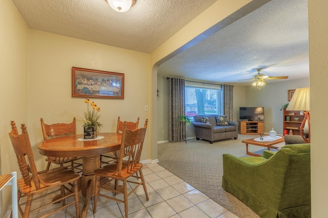 carpeted dining space with ceiling fan and a textured ceiling