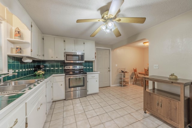 kitchen featuring light tile patterned floors, appliances with stainless steel finishes, backsplash, a textured ceiling, and white cabinets