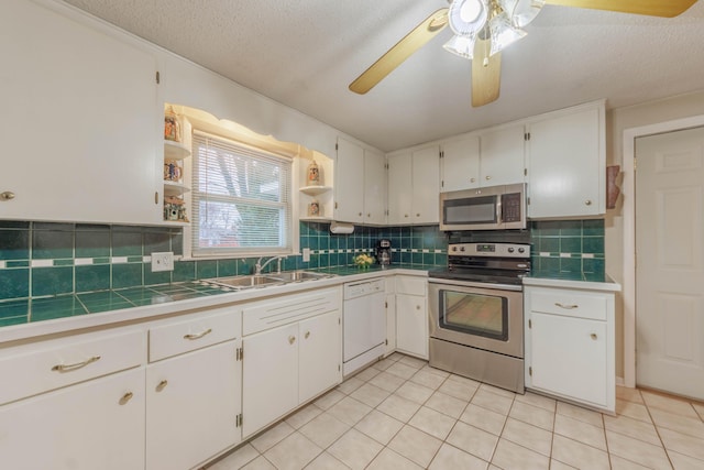 kitchen with appliances with stainless steel finishes, white cabinetry, sink, decorative backsplash, and light tile patterned floors