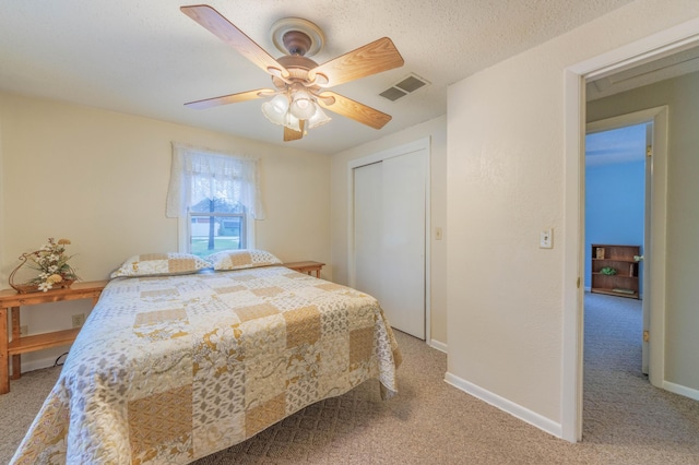 bedroom with ceiling fan, light carpet, a textured ceiling, and a closet