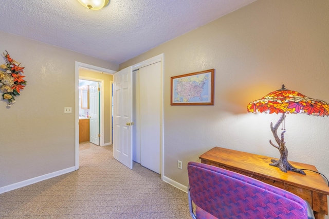 hall with light colored carpet and a textured ceiling