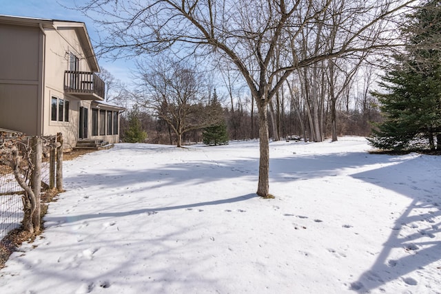 snowy yard with a balcony and a sunroom