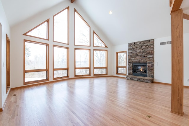 unfurnished living room featuring a fireplace, light hardwood / wood-style flooring, and high vaulted ceiling