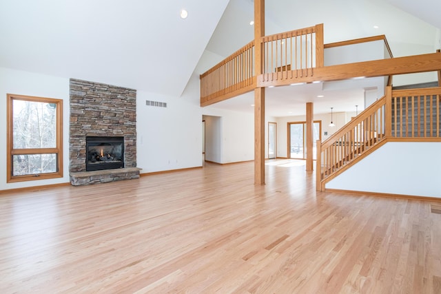 unfurnished living room with a stone fireplace, high vaulted ceiling, and light hardwood / wood-style flooring