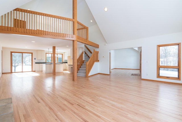 unfurnished living room featuring light hardwood / wood-style flooring and high vaulted ceiling