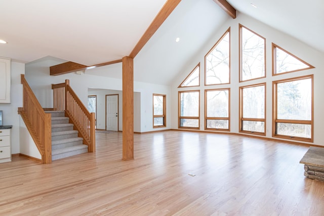 unfurnished living room with beamed ceiling, high vaulted ceiling, and light hardwood / wood-style flooring