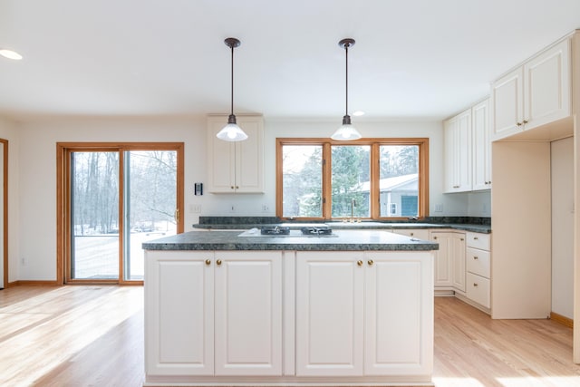 kitchen featuring pendant lighting, sink, white cabinets, white gas cooktop, and light wood-type flooring