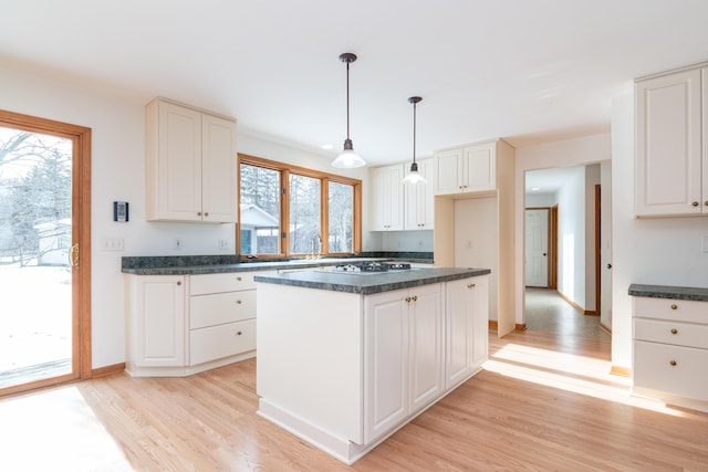 kitchen featuring white cabinetry, decorative light fixtures, light hardwood / wood-style floors, and a center island