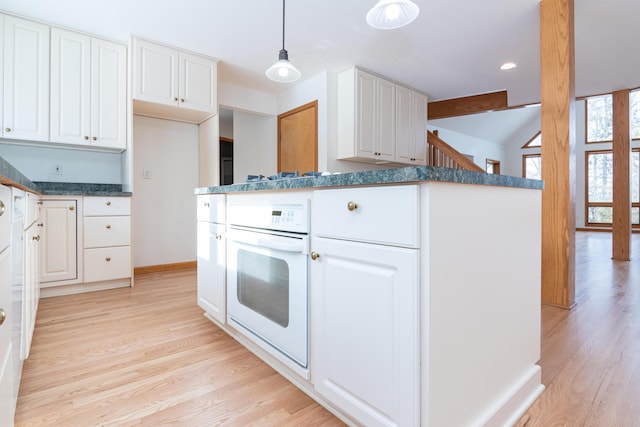 kitchen with pendant lighting, light hardwood / wood-style floors, white cabinets, and white oven