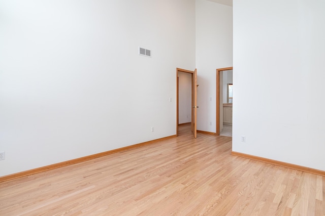 unfurnished room with a towering ceiling and light hardwood / wood-style floors