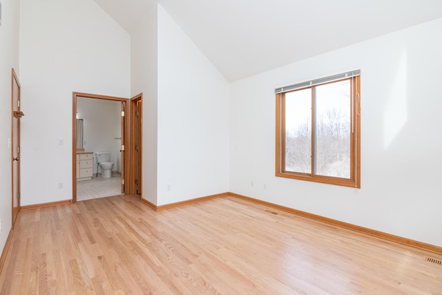 empty room featuring light hardwood / wood-style flooring and high vaulted ceiling