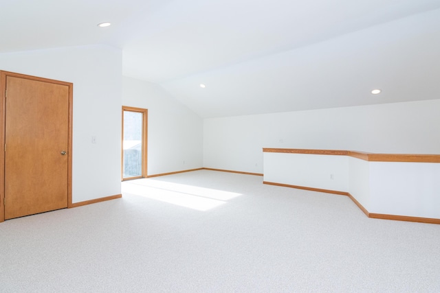 additional living space featuring lofted ceiling and light carpet