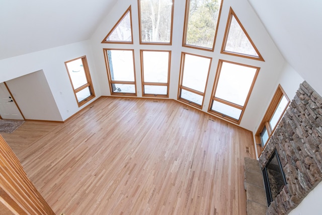 unfurnished living room with high vaulted ceiling and light wood-type flooring