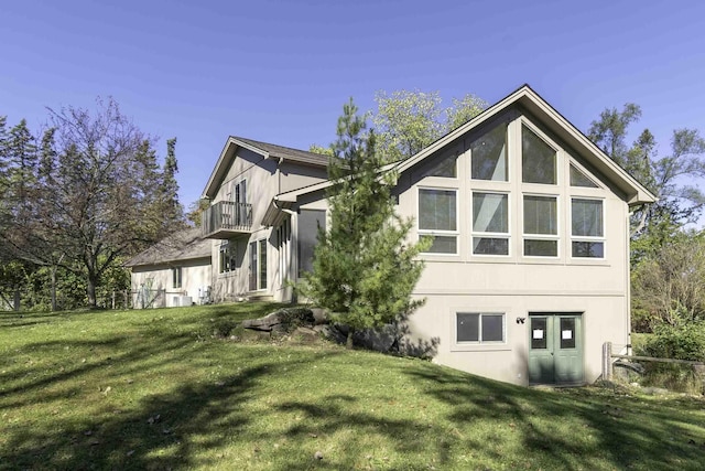 rear view of house with a lawn and a balcony