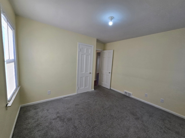 empty room with a healthy amount of sunlight and dark carpet