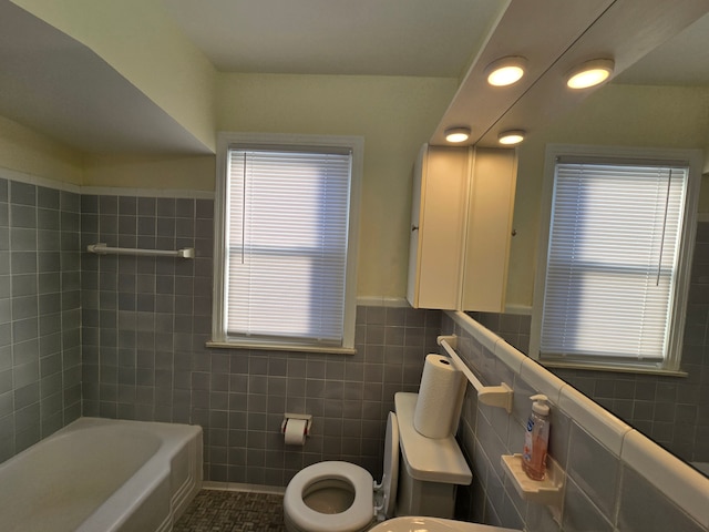 bathroom with tile walls, tile patterned floors, a bathtub, and toilet