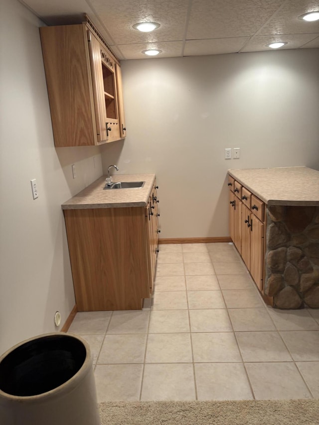 kitchen featuring a drop ceiling, sink, and light tile patterned floors