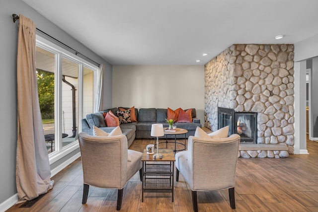 living room with hardwood / wood-style flooring and a stone fireplace