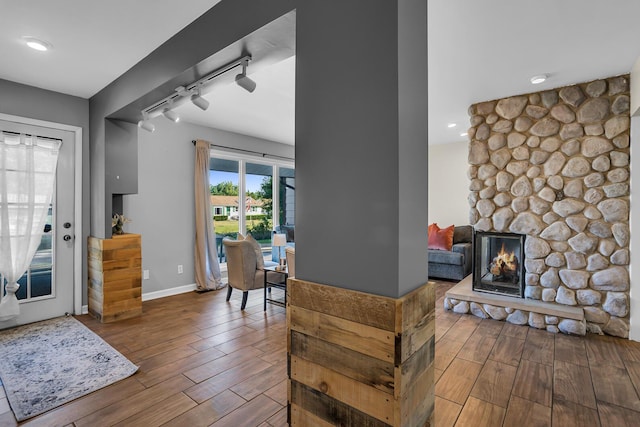 entryway featuring wood-type flooring, a fireplace, and rail lighting