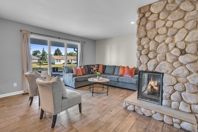 living room featuring a stone fireplace and light hardwood / wood-style flooring