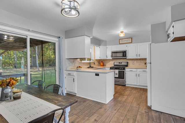 kitchen with tasteful backsplash, appliances with stainless steel finishes, dark hardwood / wood-style floors, and white cabinets