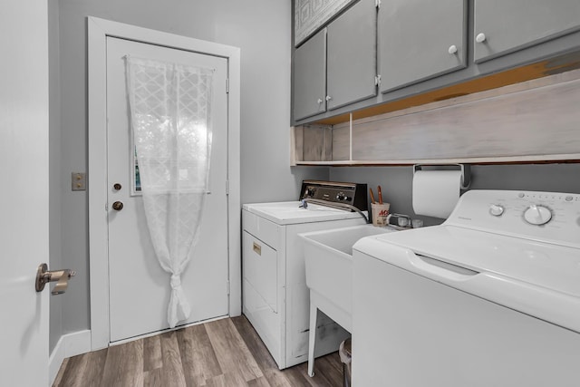 laundry room featuring cabinets, independent washer and dryer, and light hardwood / wood-style floors