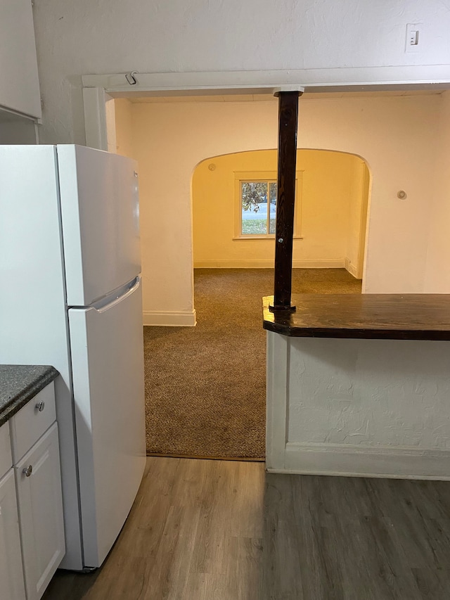 1192 S Belsay Rd, Burton, MI 48509 - kitchen featuring freestanding refrigerator, arched walkways, white cabinets, dark countertops, and wood finished floors