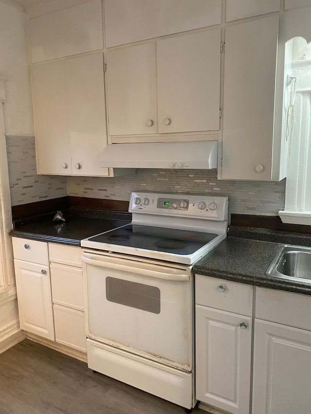 1192 S Belsay Rd, Burton, MI 48509 - kitchen featuring white range with electric cooktop, under cabinet range hood, white cabinetry, decorative backsplash, and dark countertops