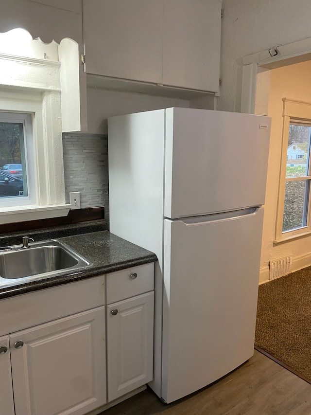 kitchen with sink, white cabinetry, white refrigerator, wood-type flooring, and decorative backsplash