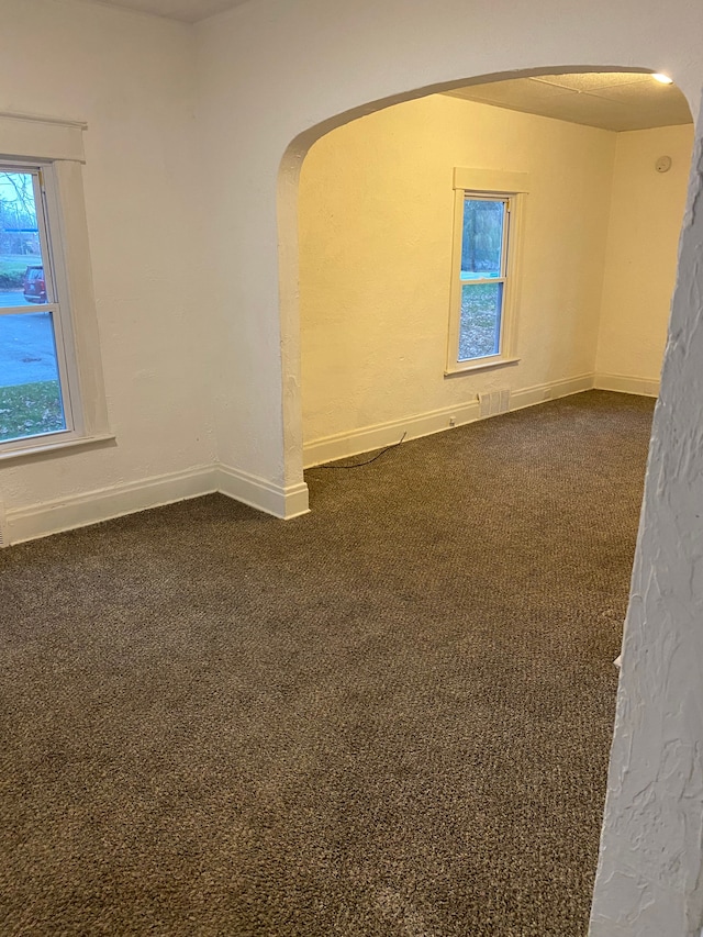 1192 S Belsay Rd, Burton, MI 48509 - empty room with arched walkways, dark colored carpet, and baseboards