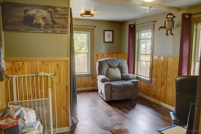 sitting room with hardwood / wood-style floors and wooden walls