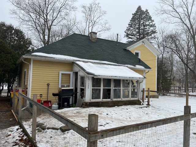 snow covered house featuring a sunroom