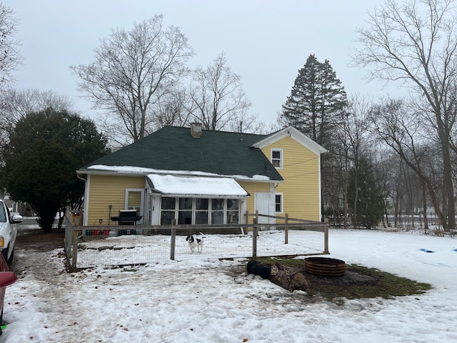 snow covered back of property featuring a sunroom and central air condition unit