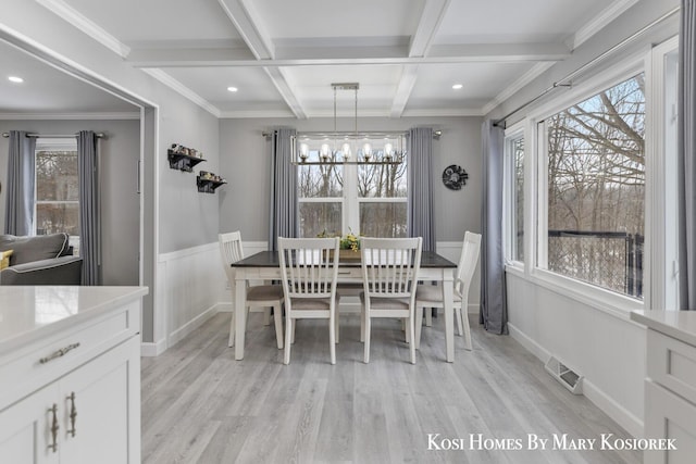 dining room with an inviting chandelier, beam ceiling, a wealth of natural light, and light wood-type flooring