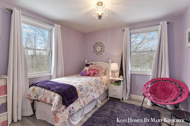 bedroom with multiple windows, hardwood / wood-style floors, and a notable chandelier