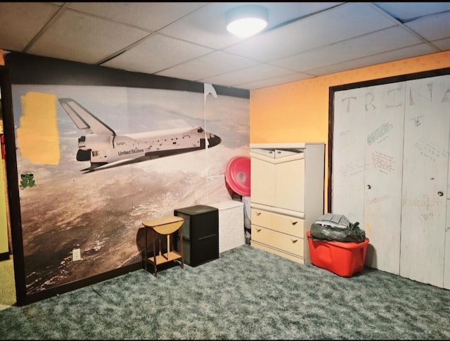 basement featuring a paneled ceiling and carpet