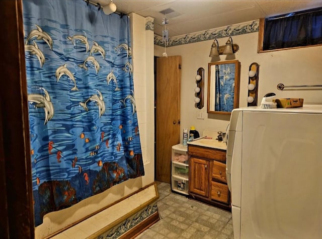 bathroom with vanity, washer / dryer, and a shower with shower curtain