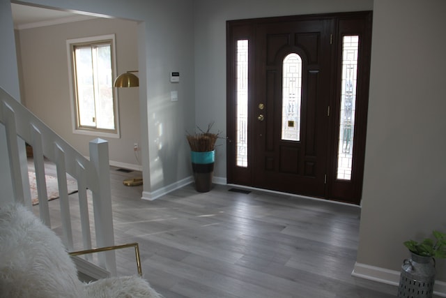 foyer entrance featuring crown molding and hardwood / wood-style floors