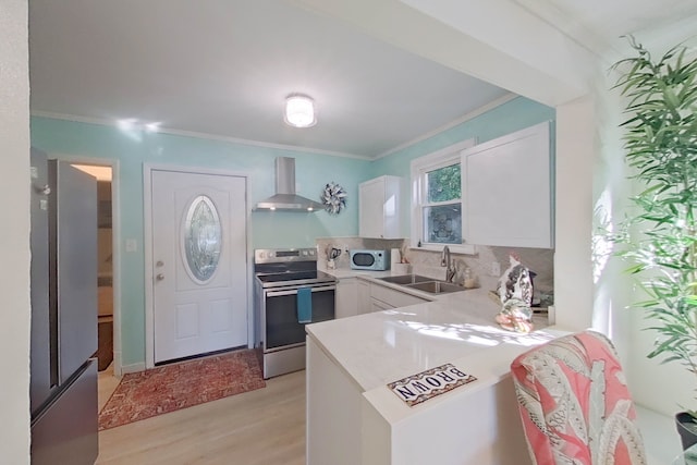 kitchen featuring stainless steel appliances, sink, wall chimney range hood, and white cabinets