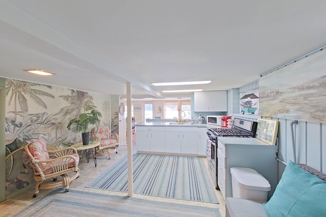 kitchen featuring stainless steel gas stove, sink, and white cabinets