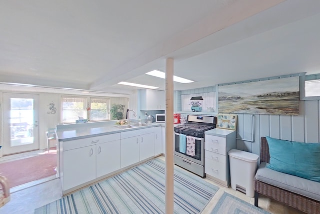 kitchen with white cabinetry, gas stove, sink, and kitchen peninsula