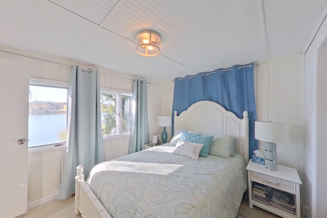 bedroom with light wood-type flooring and a water view